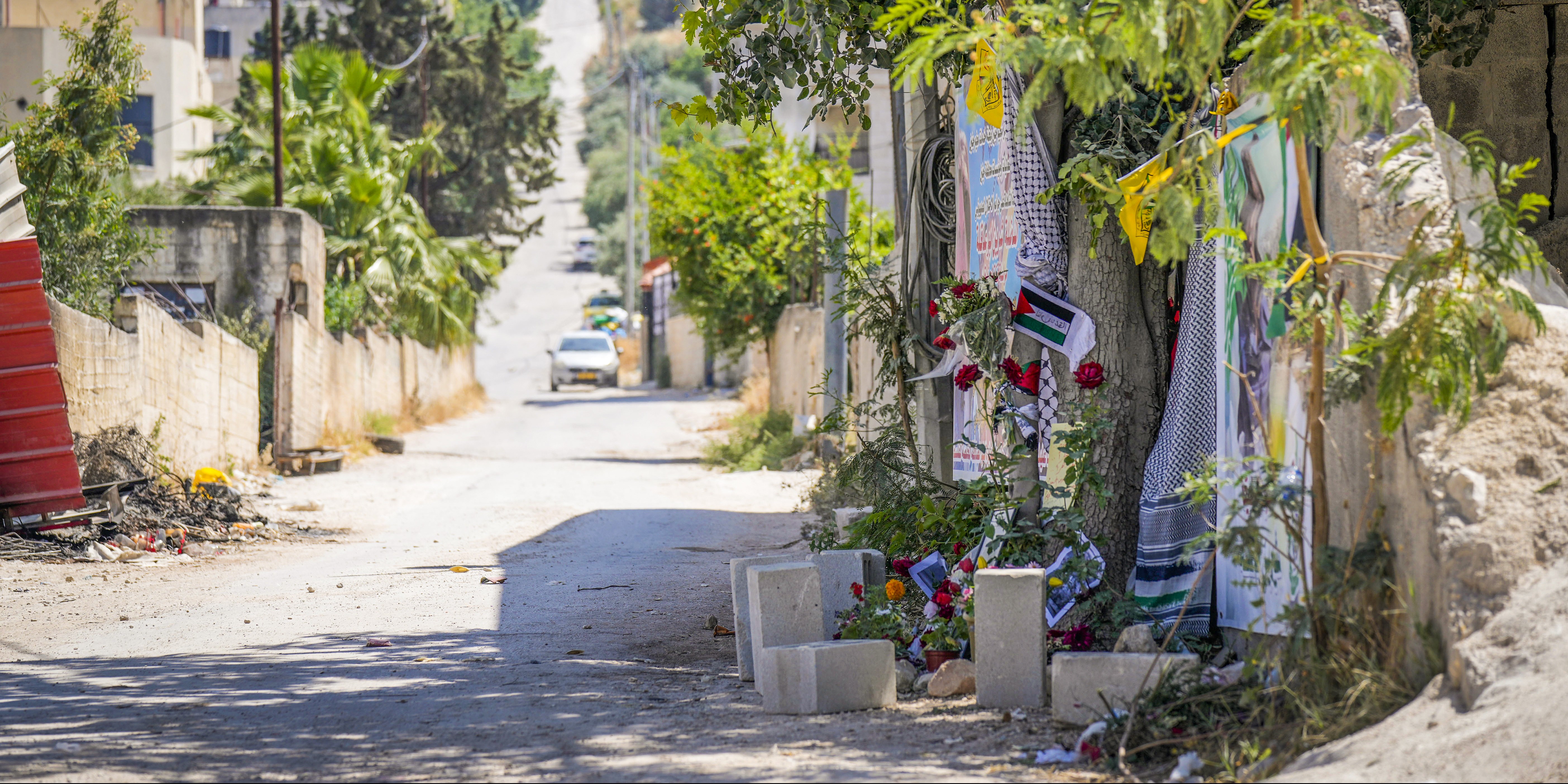 Flowers, flags and other memorabilia create a makeshift memorial at the site where  veteran Palestinian-American reporter Shireen Abu Akleh was shot and killed, in the West Bank city of Jenin, May 19, 2022. Almost two weeks after the death of Abu Akleh, a reconstruction by The Associated Press lends support to assertions from both Palestinian authorities and Abu Akleh's colleagues that the bullet that cut her down came from an Israeli gun. (AP Photo/Majdi Mohammed)