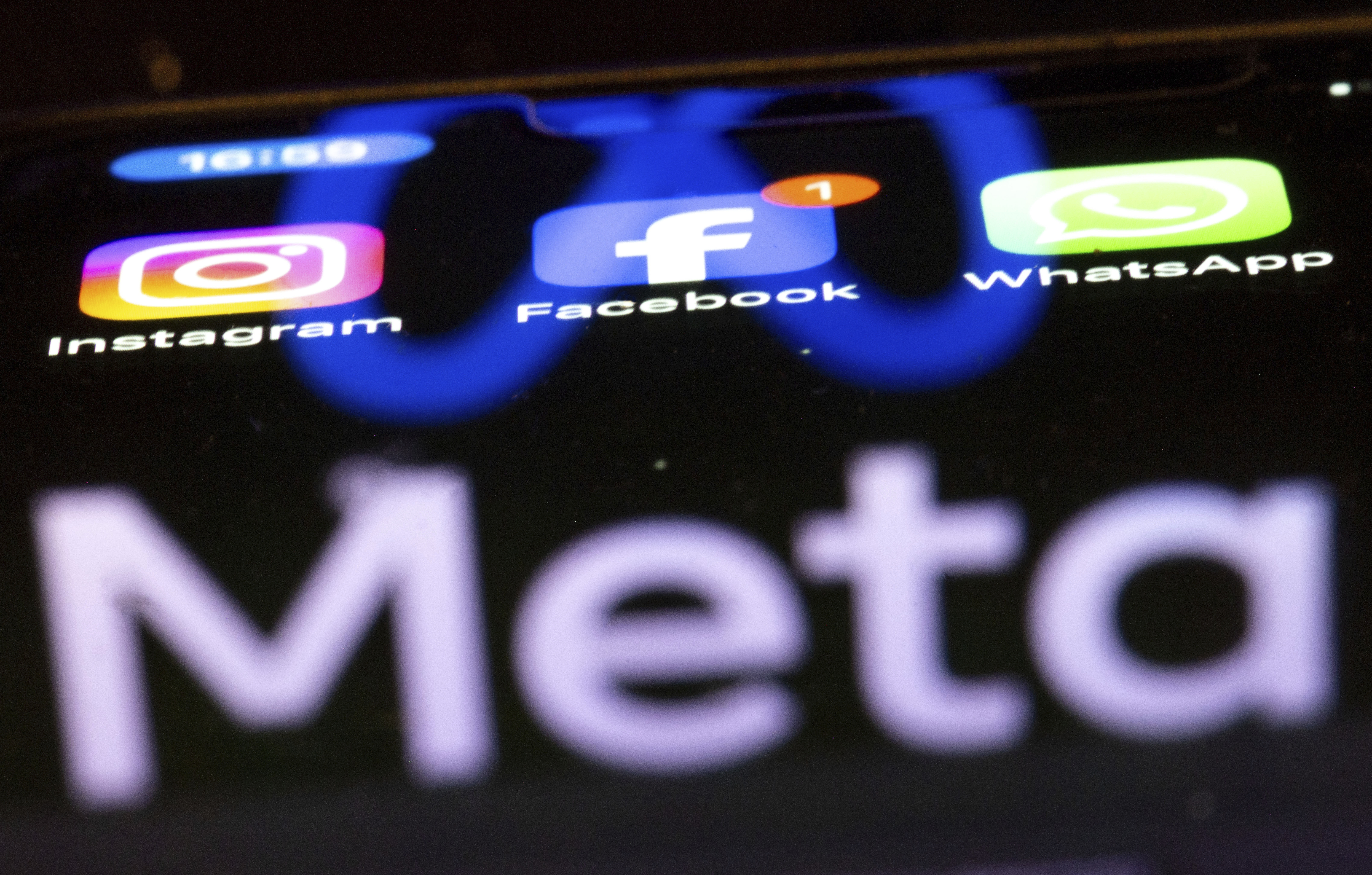 The Instagram, Facebook and WhatsApp apps seen on a smartphone, reflecting the logo of Meta.