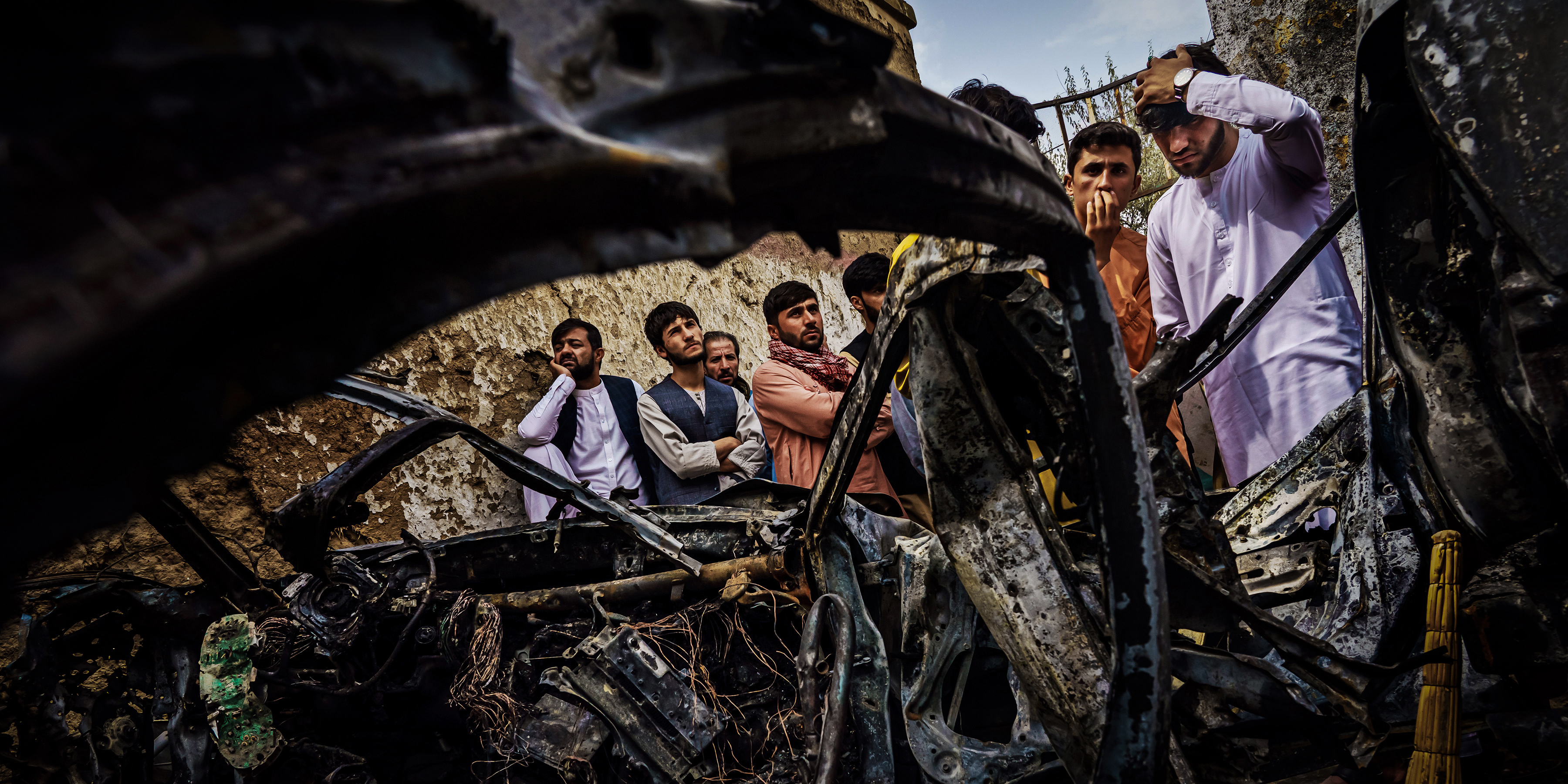 Family members and neighbors of the Ahmadi family gather to examine the wreckage caused by a hellfire missile launched from a U.S. drone that targeted a vehicle parked inside a residential compound in the Khwaja Burgha neighborhood in Kabul, Afghanistan, on Aug. 30, 2021. The U.S. military says that the air strike was meant to target ISIS-K militants and retaliate for an airport bombing carried out by the terror group. Instead, it took the lives of 10 civilians  members of Emal Ahmadis family, including seven children. The U.S. would eventually call the strike a tragic mistake.