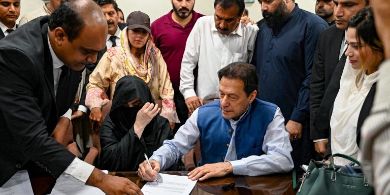 Pakistan's former Prime Minister, Imran Khan (C) along with his wife Bushra Bibi (C, left) signs surety bonds for bail in various cases, at a registrar office in the High court, in Lahore on July 17, 2023. (Photo by Arif ALI / AFP) (Photo by ARIF ALI/AFP via Getty Images)